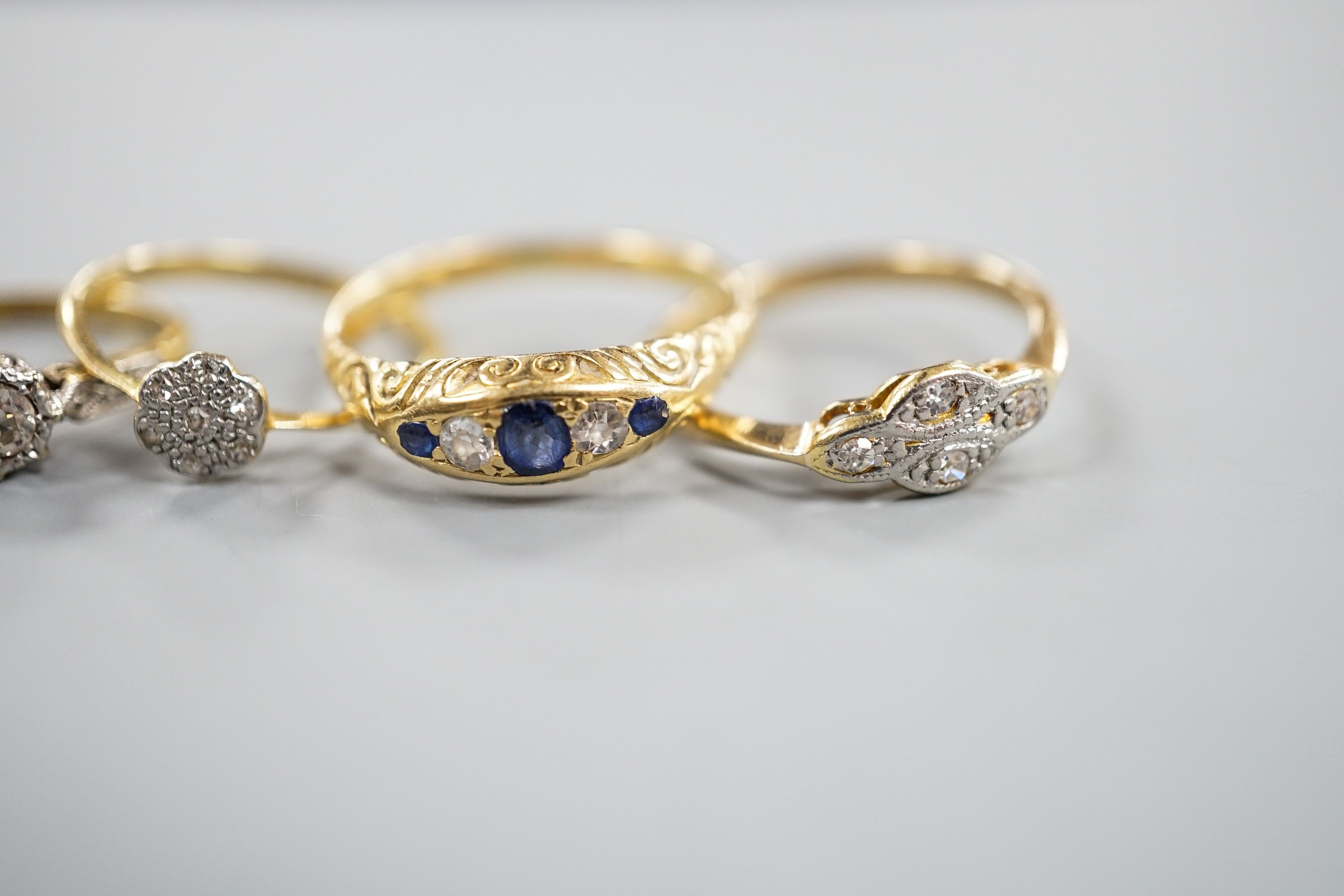 Two 18ct and diamond rings, including small cluster and single stone, sizes L & H, an 18ct sapphire and diamond ring, size O, gross 7.3 grams and two other yellow or white metal and gem set rings, gross 3.6 grams.